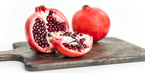 Granatapfel / johannes sommer - herzblut, johannes sommer Das Fotos zeigt einen ganzen und eine aufgebrochenen Granatapfel auf einem Jausenbrett.